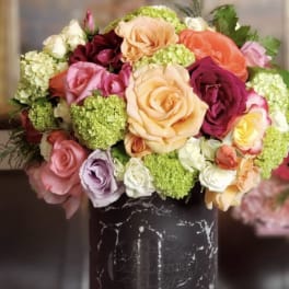 Mixed bouquet of roses and green hydrangeas in a black vase
