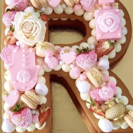 Decorated number-shaped cake with pink candies, strawberries, and a white rose