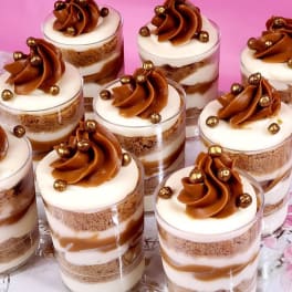 Dessert cups topped with caramel frosting and gold sprinkles