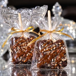 Two chocolate-dipped treats in clear gift bags with gold ribbons