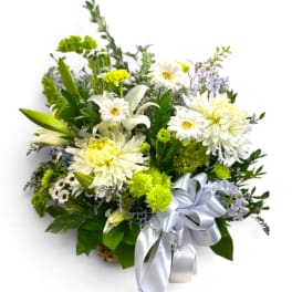 White lilies and daisies in a basket with a silver ribbon