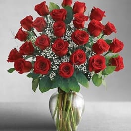 Red roses arranged in a clear glass vase with baby's breath