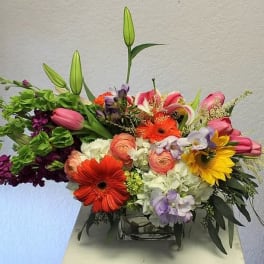 Mixed bouquet with lilies, gerbera daisies, roses, and hydrangeas in a glass vase