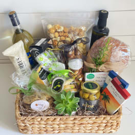 Gift basket with wine, snacks, bread, olives, and a small succulent