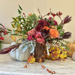 Mixed floral arrangement with pink and orange roses in a wood vase