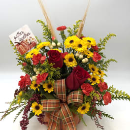 Fall floral arrangement with red roses, yellow daisies, and a plaid bow in a pumpkin container