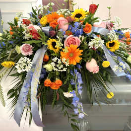Large casket spray with mixed colorful flowers and blue ribbons