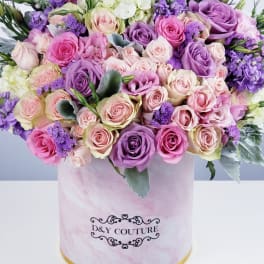 Mixed pink and purple roses in a round hat box