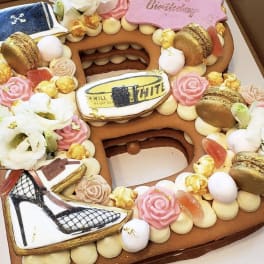 Decorated number-shaped cake with flowers, macarons, and birthday plaques