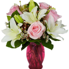 Pink roses and white lilies in a pink glass vase