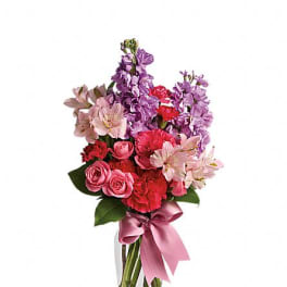 Pink and purple mixed bouquet in a clear glass vase with a ribbon