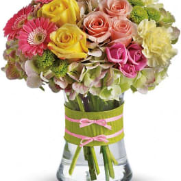Mixed bouquet of roses, gerbera daisies, and hydrangeas in a glass vase