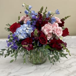 Mixed bouquet of red and pink roses with blue hydrangea in a glass vase