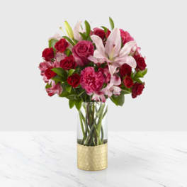 Pink and red bouquet with lilies and roses in a glass vase