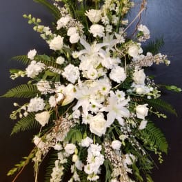 Tall white funeral spray with lilies, roses, and snapdragons