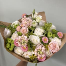 Bouquet of white and pink roses with green pompons and paper wrap