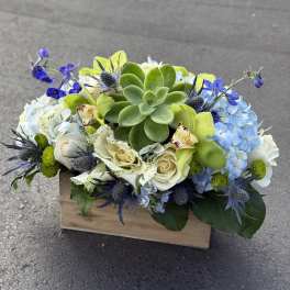 Succulent and blue-white floral arrangement in a wooden box