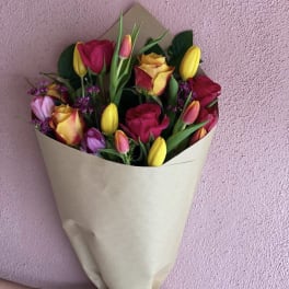Bouquet of multicolored tulips and roses wrapped in beige paper