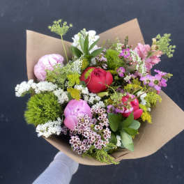 Mixed bouquet of pink and white flowers wrapped in brown paper