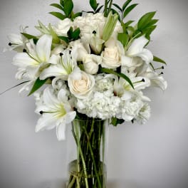 White lilies and roses arranged in a clear glass vase