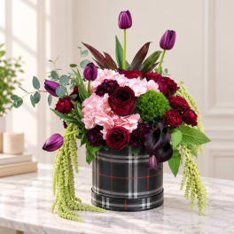 Bouquet of purple tulips, roses, and pink blooms in a plaid hatbox