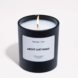 Lit scented candle in a black glass jar with a white label
