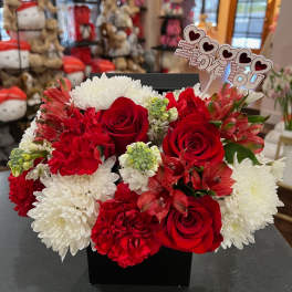 Red and white flower arrangement in a black box with a "I Love You" topper
