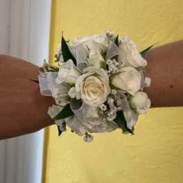 White rose wrist corsage with silver ribbon on a person's wrist