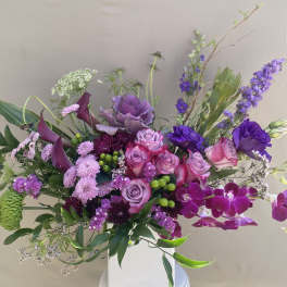 Purple and pink floral arrangement in a white vase