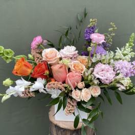 Mixed bouquet of roses, orchids, and snapdragons in a white vase