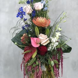 Tall mixed bouquet with roses, orchids, and anthuriums in a vase