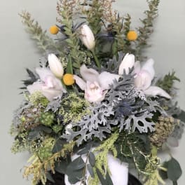 White tulips and pale orchids in a white vase with silvery foliage