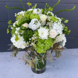 White and green floral arrangement in a glass vase