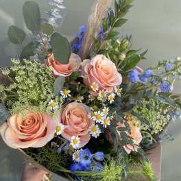 Peach roses with blue flowers and daisies in a hand-tied bouquet