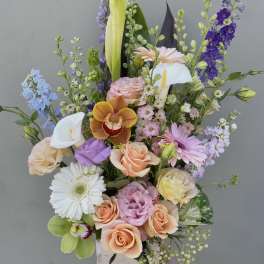 Mixed pastel flower arrangement in a wooden box with orchids and roses