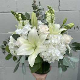 White lily and rose bouquet with hydrangeas in a glass vase