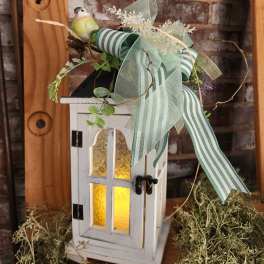 Decorative white lantern with ribbon and a small bird figurine