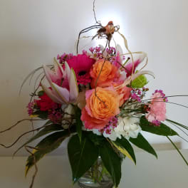 Mixed bouquet of pink and orange flowers in a glass vase