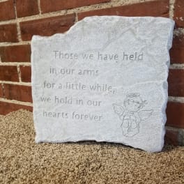 A white memorial stone plaque with an angel engraving and engraved text.