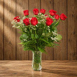 Red roses in a clear glass vase with white filler flowers