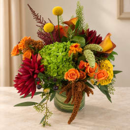 Colorful mixed bouquet in a glass vase with orange, red, yellow, and green blooms.
