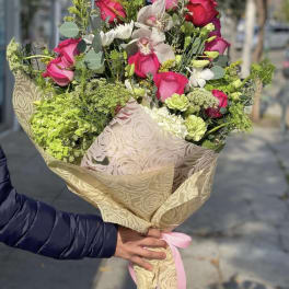 Bouquet of pink roses and white orchids wrapped in patterned paper