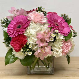 Pink gerberas and carnations in a clear glass vase