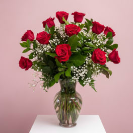 Red roses arranged in a clear glass vase with baby's breath