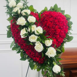 Heart-shaped floral arrangement with red flowers and white roses