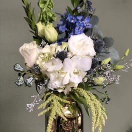 Mixed bouquet in a metallic vase with white, blue, and green flowers