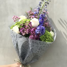 Hand-tied bouquet of white roses, blue hyacinth, and pink filler flowers
