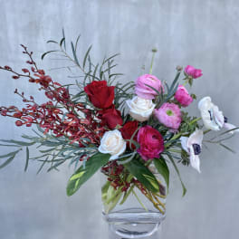 Mixed bouquet of red, pink, and white flowers in a clear glass vase