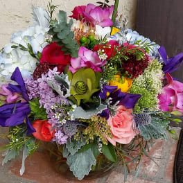 Colorful mixed bouquet with roses, orchids, and hydrangeas in a low container