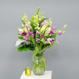Mixed bouquet of lilies and pink-purple flowers in a glass vase